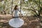 Young European beautiful girl in white bridal marriage dress posing on swing in forest trees on the ocean sea beach