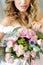 Young european bride wearing white dress with bouquet at photo studio.