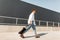 Young european hipster man in a white shirt in blue jeans in fashionable sandals with a black bag walks on the street