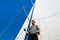 Young european man standing at edge of yacht looking at sea. Travelling on old boat with sail. Luxury lifestyle.