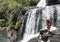 Young european tourist girl sitting on the edge of the Baker`s falls in the national park