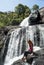 Young european tourist girl sitting on the rock at the Baker`s falls in the national park