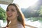 Young european woman is boating on a lake. Girl smiling showing teeth, sitting into small boat at sunset on the river in the