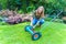 Young european woman reparing lawn mower in garden