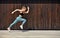 Young European woman sports model posing outdoors along wooden wall, running, jumping, jogging, stretching, wearing in