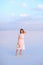 Young european woman in white dress walking on sand and keeping