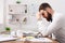 Young exhausted businessman thinking about solution in white office. Papers on the desk