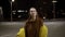 Young expansive woman sensually dancing outside in yellow jacket. Feel free, smiling. Handhelded footage