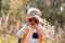 Young explorer watching with binoculars of birds in the high grass