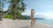 Young explorer woman, seats on the beach blanket, stands up and walks by the send to the sea