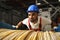 A young factory workman rolls heavy coil of electric cable