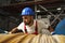 A young factory workman rolls heavy coil of electric cable