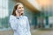 Young famale calling on a smartphone. Attractive businesswoman talking by phone. Office building Background. Technology