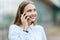 Young famale calling on a smartphone. Attractive businesswoman talking by phone. Office building Background. Technology