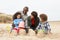 Young Family Building Sandcastle On Beach Holiday