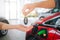 Young family buying first electric car in the showroom. Close-up of male hand giving car key to female hand on battery