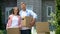 Young family with cardboard boxes looking at camera, moving to new house, credit