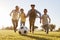 Young family chasing after a football in a park