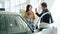 Young family with child buying car in dealership, man and woman doing high-five