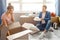 Young family couple bought or rented their first small apartment. Guy sit on floor and hold white plates. Young woman