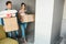 Young family couple bought or rented their first small apartment. Happy cheerful people enter room with boxes of stuff