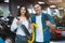 Young family couple handsome man and beautiful brunette woman holding charging cable for electric car , looking satisfied