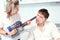 Young family couple have fun in home kitchen. Wife cleans her husband's face, which is covered in flour, with vacuum