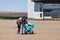 Young family couple with mom and dad are walking outdoors with a baby stroller of blue color in which the newborn child in a large