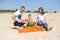 Young family is eating a watermelon together on the sandy beach