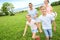 Young family of four running on green grass