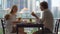 Young family having a breakfast, lunch on their balcony in a skyscraper with a view on a whole downtown of the city