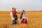 Young family having fun in countryside. Parents and small childrens in wheat field