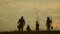 Young family having fun outdoors in their farm. Silhouette family of four planting a new tree at sunset. Teamwork happy