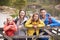 Young family leaning on a wooden fence in the countryside, looking at camera, close up