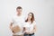 Young family, a man and a woman in white clothes in a bright room on the background of cardboard boxes and things.