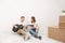 Young family, a man and a woman in white clothes in a bright room on the background of cardboard boxes and things.