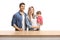 Young family of a mother, father and a baby girl posing behind a wooden counter