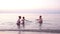 Young family playing red toy boat at sunset