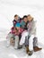 Young Family Sitting On A Sled In The Snow