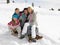 Young Family Sitting On A Sled In The Snow