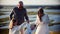 Young family standing on the wheat field - father and mother holding hands with their baby and swinging her forward and