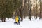 Young family with stroller in yellow and blue clothes in winter sunny day in park. Concept of happy family walking, love,
