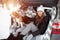 A young family of travelers woman are sitting in the trunk of their car in an embrace with their friend dog Beagle.