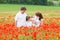 Young family with two kids - son and newborn daughter - posing in poppy flower field