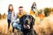 A young family with two small children and a dog on a meadow in autumn nature.