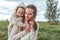 Young family, woman mom happy smiling, little boy in a sweater with hood hugs mom, rest in field, concept parenting