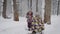 A young family in the wood. Mother with the daughter cheerfully spend time in the winter wood. The small child and