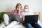 Young family works remotely from home on bed at the computer. Quarantined couple coronavirus in medical masks. Stay home