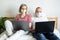 Young family works remotely from home on bed at the computer. Quarantined couple coronavirus in medical masks. Stay home