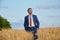 Young farmer businessman in shirt and tie inspects his fields with crops